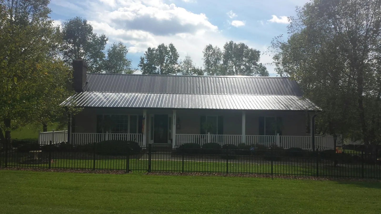 Gray metal roof on a brick ranch with a full width front porch — Gutter Guard Installation work by our crew in Nelsonville
