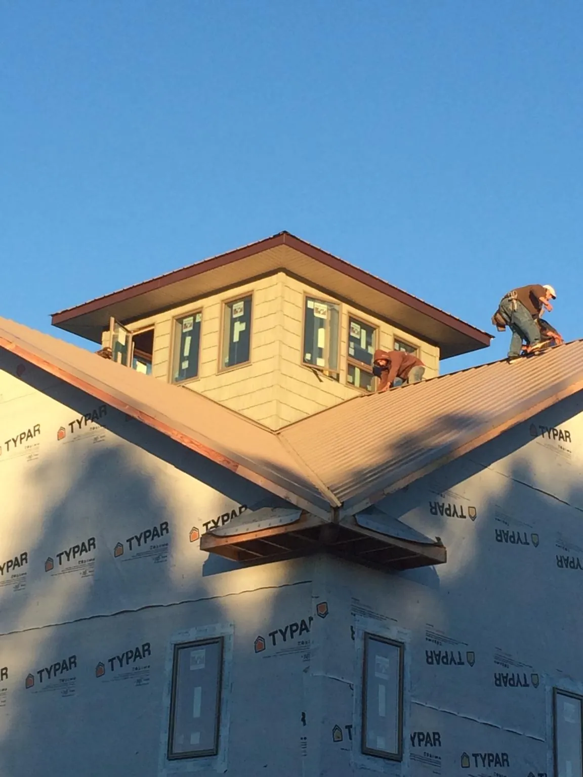 Roofers working around a rooftop cupola on a new metal roof at sunset — Roof Waterproofing in Nelsonville by Roofing Brothers